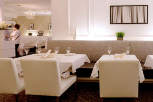 Two tables set up for dining with white table cloths and napkins.