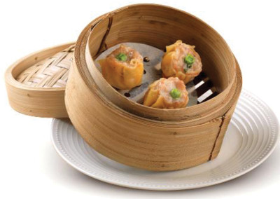 Siu Mai is pork and shrimp dim sum sitting in a bamboo steamer on a serving plate.