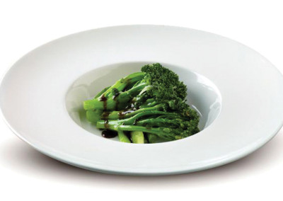Gai Lan with oyster sauce in a white bowl.