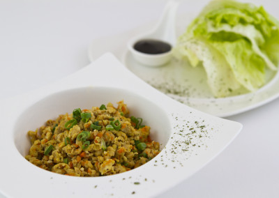 Crystal lettuce wrap with filler in side plate and fresh lettuce leafs on the right.