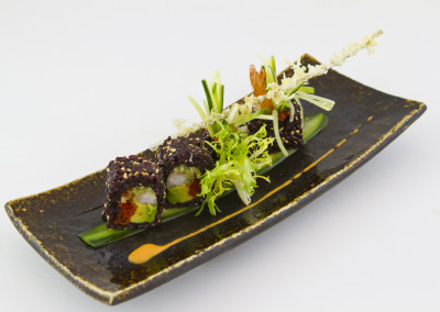 Four sections of our dynamite black maki rolls on a rectangular plate.