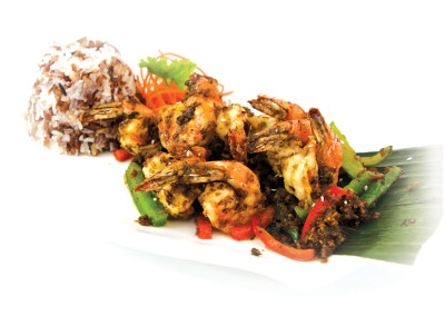Several garlic seasoned shrimp served with sweet peepers on a banana leaf.
